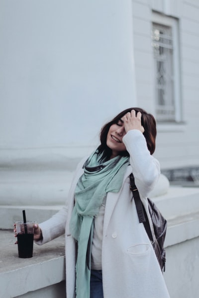 一名女子手持一次性杯子靠近白色油漆的建筑物